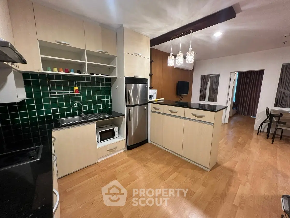 Modern kitchen with open layout and stainless steel appliances in stylish apartment.