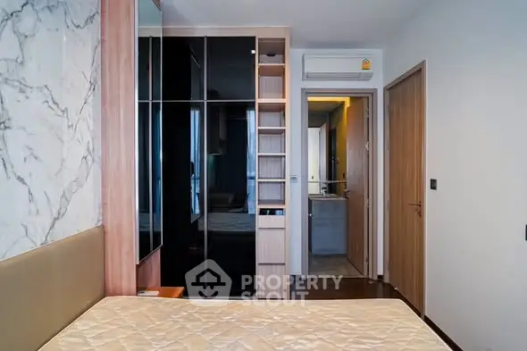 Modern bedroom with built-in wardrobe and marble accent wall in stylish apartment.