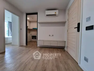 Modern apartment interior with wooden flooring and air conditioning, featuring a compact kitchen and open layout.