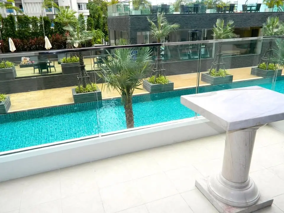 Luxurious poolside view from a modern balcony with elegant marble table, perfect for relaxation and entertainment.