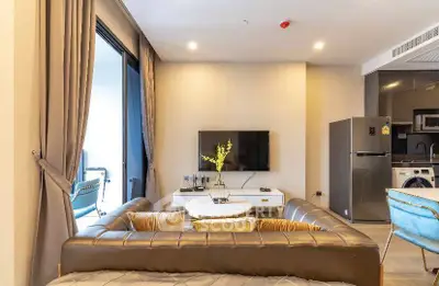 Modern living room with stylish furniture and open kitchen layout, featuring a cozy ambiance and natural light.