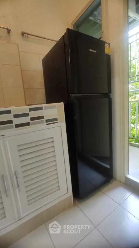 Modern kitchen corner with sleek black fridge and stylish cabinetry.