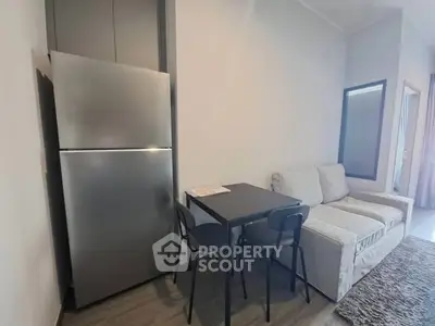 Modern compact living area with fridge, dining table, and cozy sofa in a stylish apartment.