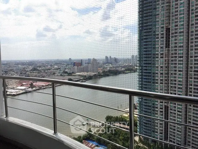 Stunning high-rise balcony view overlooking river and cityscape, perfect for urban living enthusiasts.