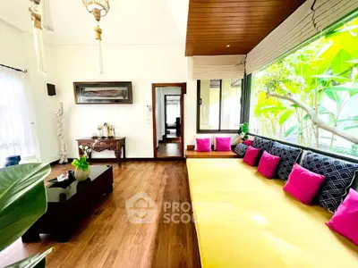 Spacious living room with vibrant decor and large windows overlooking lush greenery.