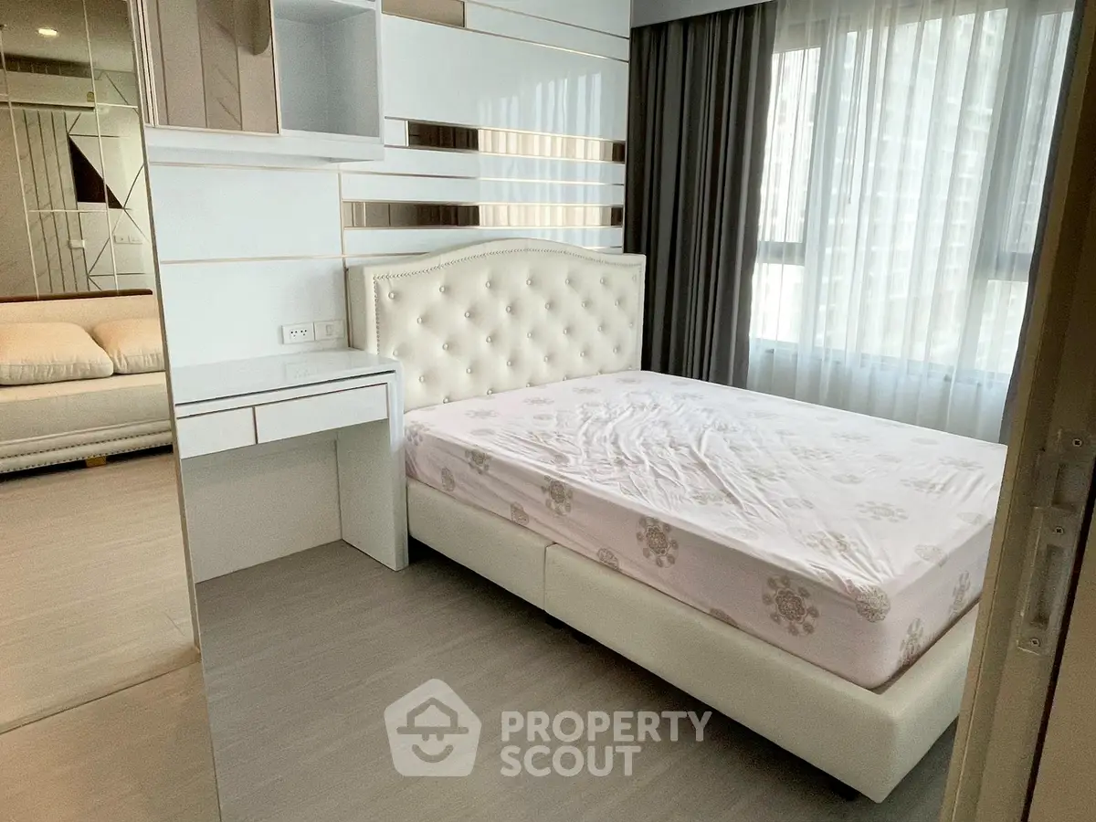 Modern bedroom with elegant white decor and large windows for natural light.