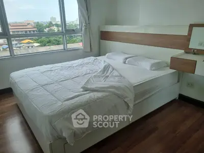 Spacious bedroom with large window offering city views and modern furnishings.