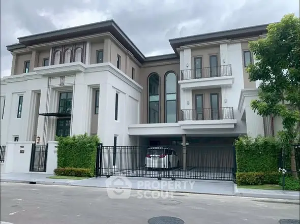 Luxurious modern three-story house with elegant facade and gated driveway.