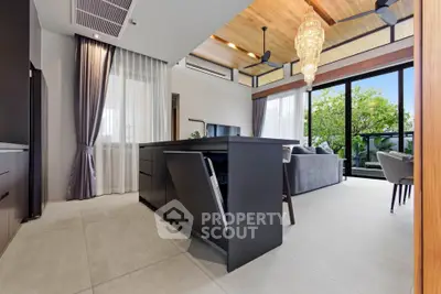 Luxurious open-plan living room with modern kitchen and large windows overlooking greenery.
