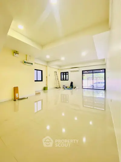 Spacious open-plan living room with glossy floors and large windows for natural light.