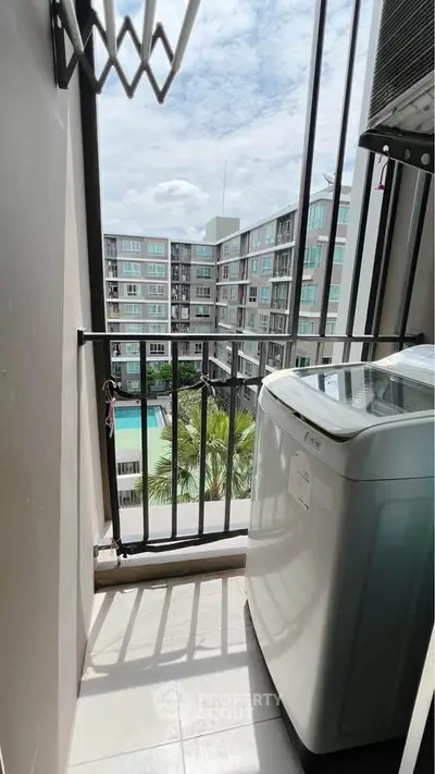 Modern apartment balcony with washing machine and pool view, ideal for urban living.