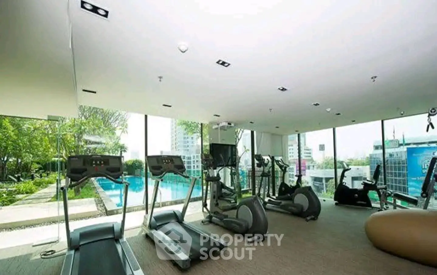 Luxurious gym with modern equipment and pool view in high-rise building