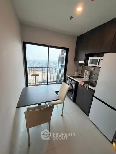 Modern kitchen with balcony view, featuring sleek appliances and dining area.