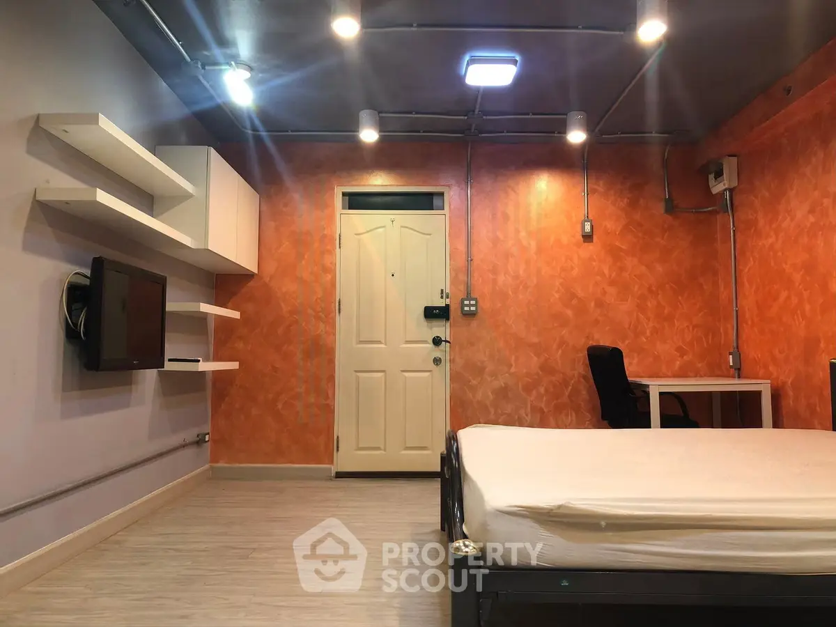 Modern bedroom with orange accent wall, sleek shelving, and minimalist furniture design.