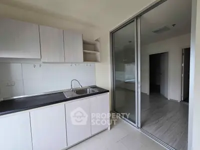 Modern kitchen with sleek cabinetry and sliding glass door in a bright apartment.
