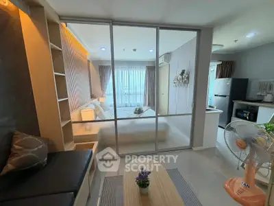 Modern studio apartment with glass partition, cozy bedroom, and compact kitchen area.