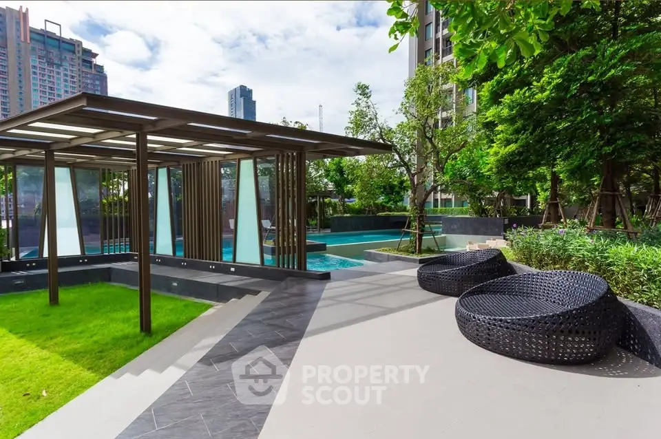 Luxurious outdoor pool area with modern seating and lush greenery in a high-rise residential complex.