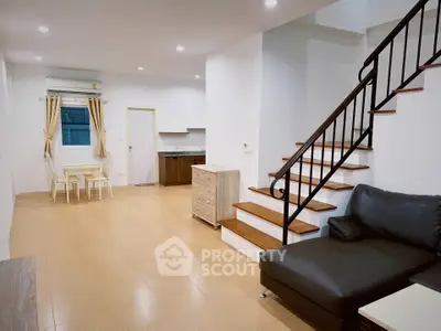 Spacious open-plan living room with modern staircase and cozy seating area.