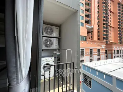 Urban balcony with laundry area and city view, featuring air conditioning units and washing machine.