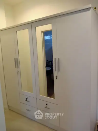 Spacious white wardrobe with mirrored doors in a modern interior setting.