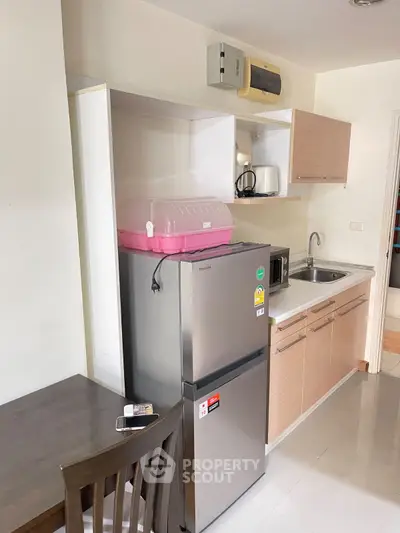 Modern compact kitchen with stainless steel fridge and sleek cabinetry