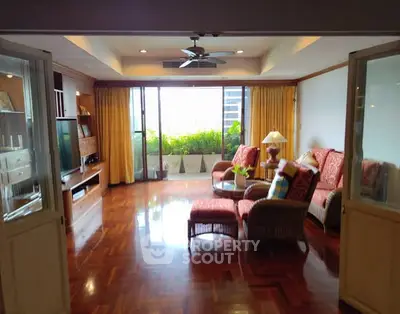 Spacious living room with elegant decor and large windows opening to a lush balcony view.