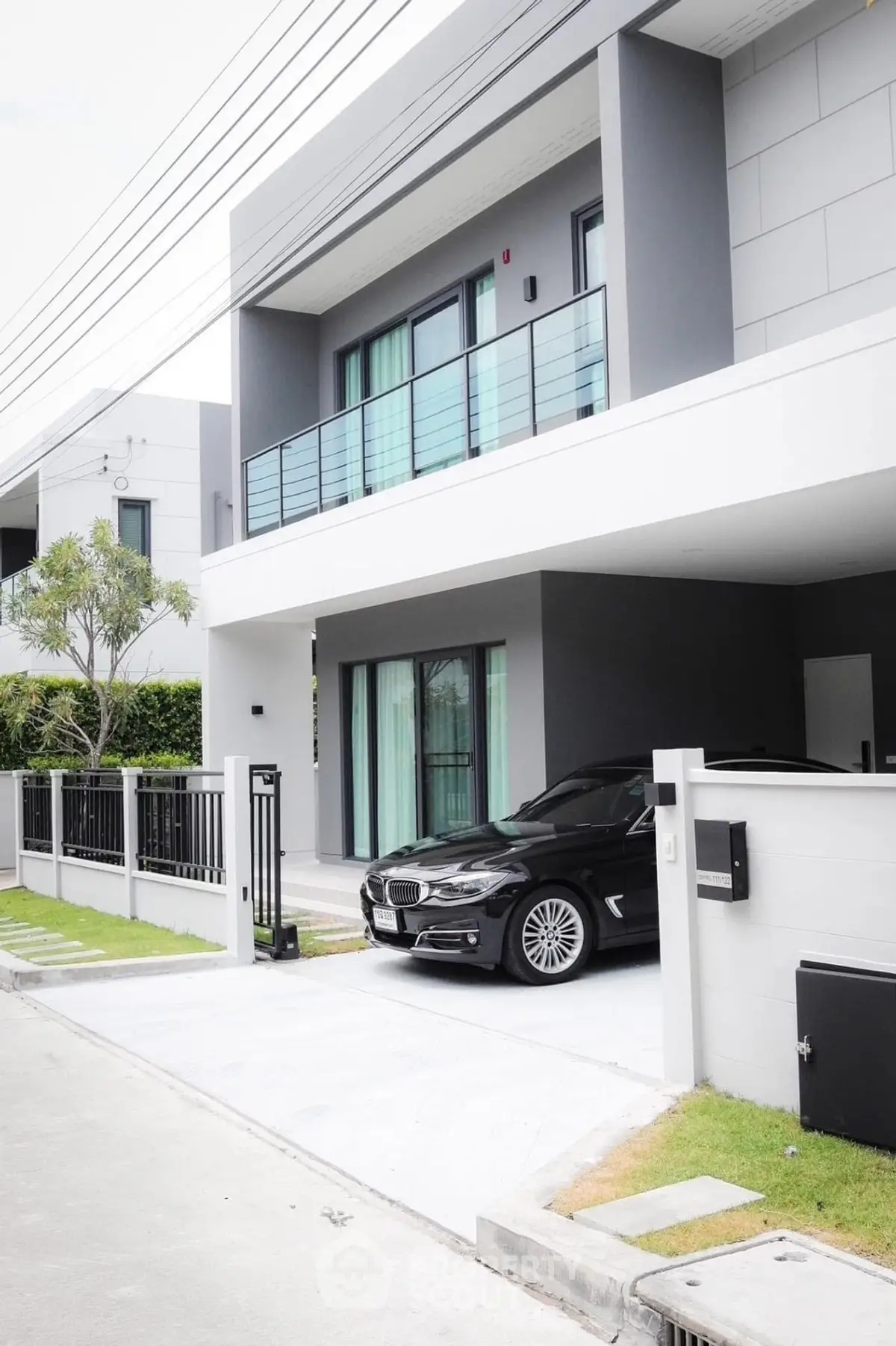 Modern two-story house with sleek design and car parked in driveway, showcasing contemporary architecture.