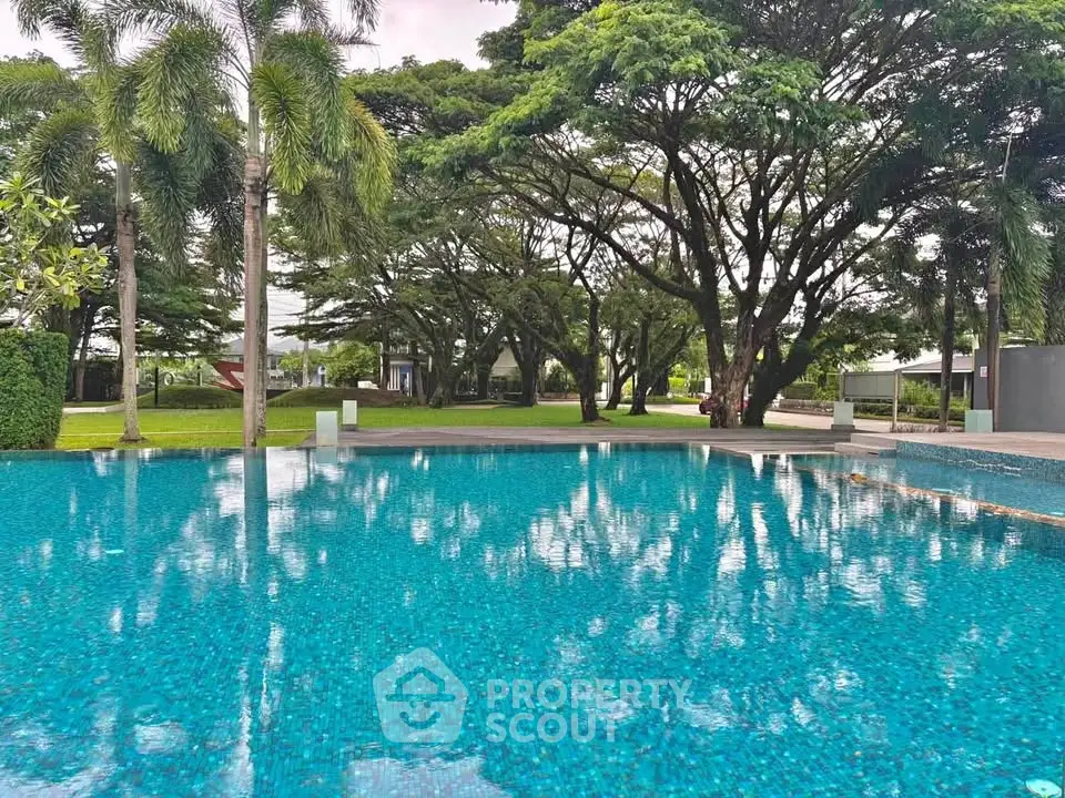 Luxurious outdoor pool surrounded by lush greenery and palm trees, perfect for relaxation and leisure.