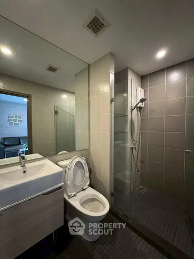 Modern bathroom with glass shower and sleek fixtures in contemporary home.