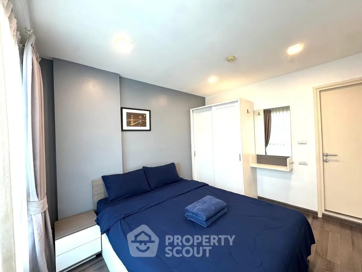 Modern bedroom with stylish decor and ample natural light, featuring a comfortable bed and sleek furnishings.