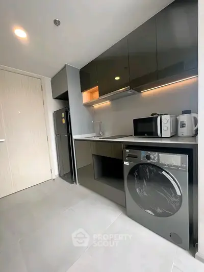 Modern kitchen with sleek cabinets, washing machine, and appliances in a stylish apartment.