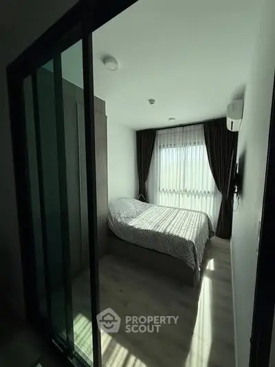 Cozy bedroom with modern design and ample natural light through large window.