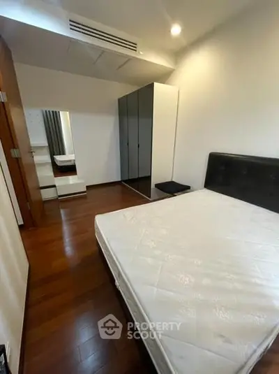Spacious bedroom with modern wardrobe and wooden flooring