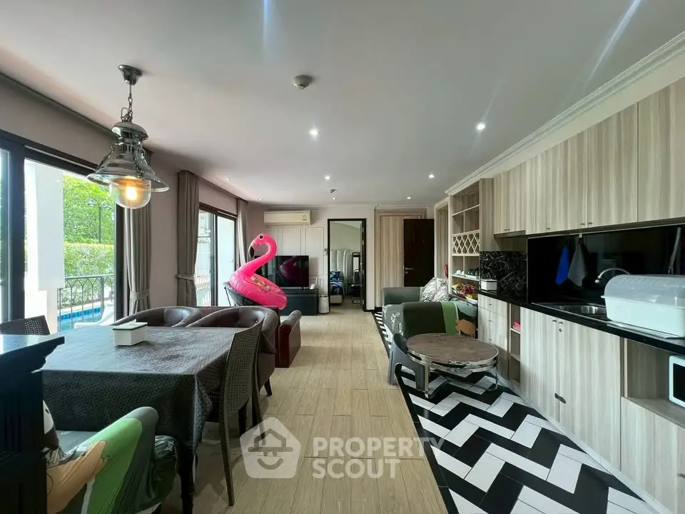 Spacious living room with modern kitchen and pool view, featuring stylish decor and ample natural light.