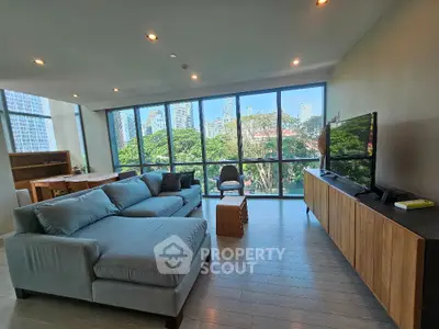 Spacious living room with large windows offering stunning city views and modern furnishings.