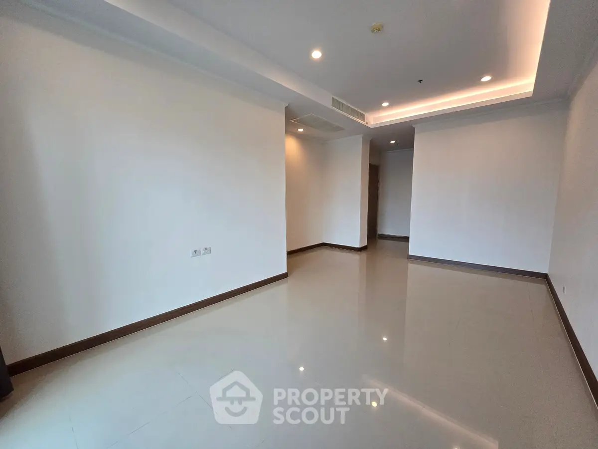 Spacious empty living room with modern lighting and glossy tiled floors.