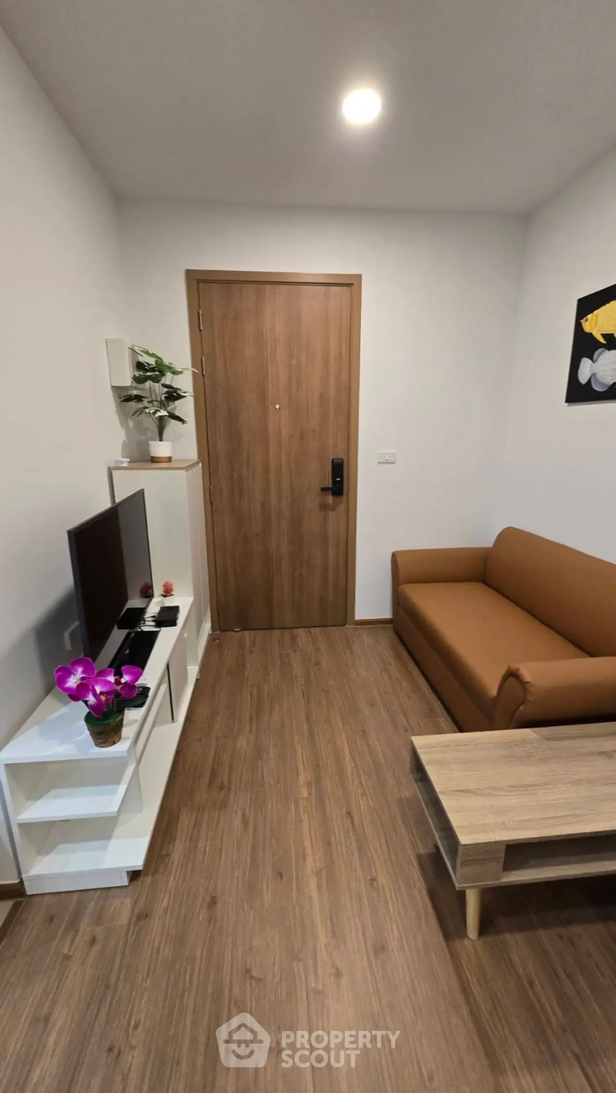 Cozy living room with modern decor and wooden flooring, featuring a comfortable sofa and entertainment unit.