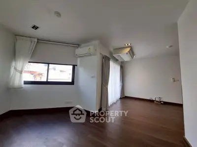 Spacious modern living room with wooden flooring and large windows for natural light.