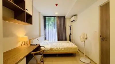 Modern bedroom with minimalist design, featuring a cozy bed, wooden desk, and large window with natural light.