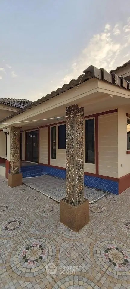 Charming single-story home with decorative columns and tiled patio, perfect for outdoor relaxation.