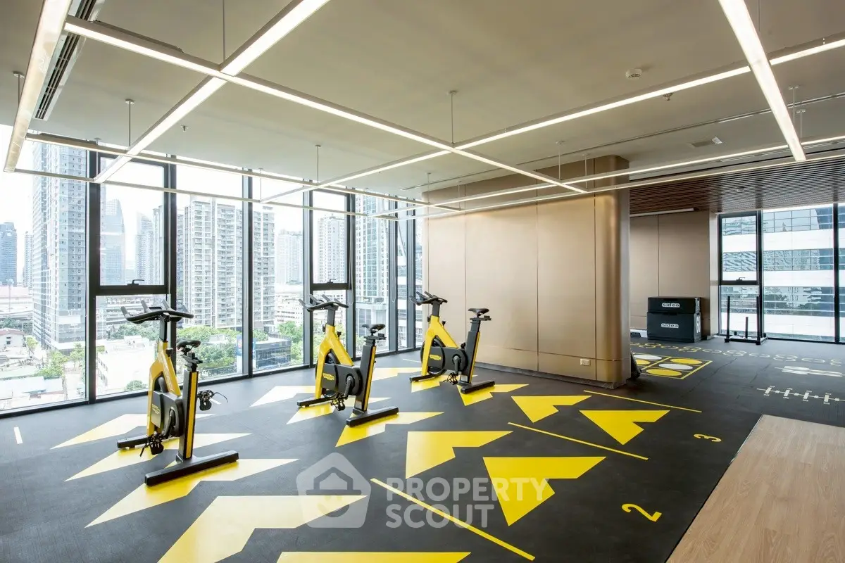 Modern gym with city view, featuring exercise bikes and sleek design.