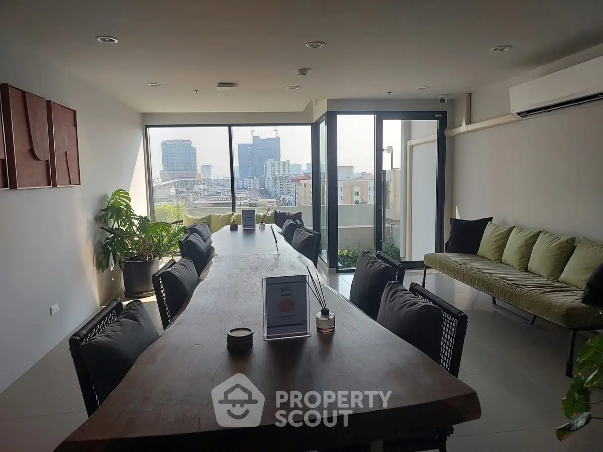 Spacious modern living room with large windows and city view, featuring stylish furniture and decor.