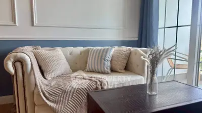 Charming living room with elegant sofa and stylish decor, featuring a cozy balcony view.