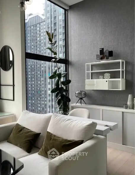 Modern living room with large windows and city view, featuring stylish decor and comfortable seating.