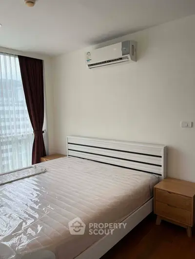 Modern bedroom with air conditioning and natural light from large window.