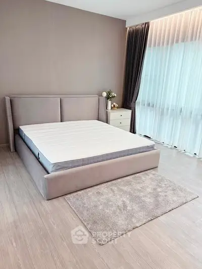 Spacious bedroom with modern design and natural light, featuring a stylish bed and elegant curtains.