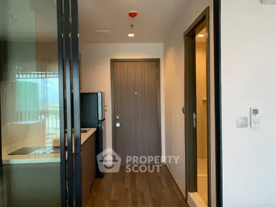 Modern apartment entrance with sleek kitchen and wooden flooring