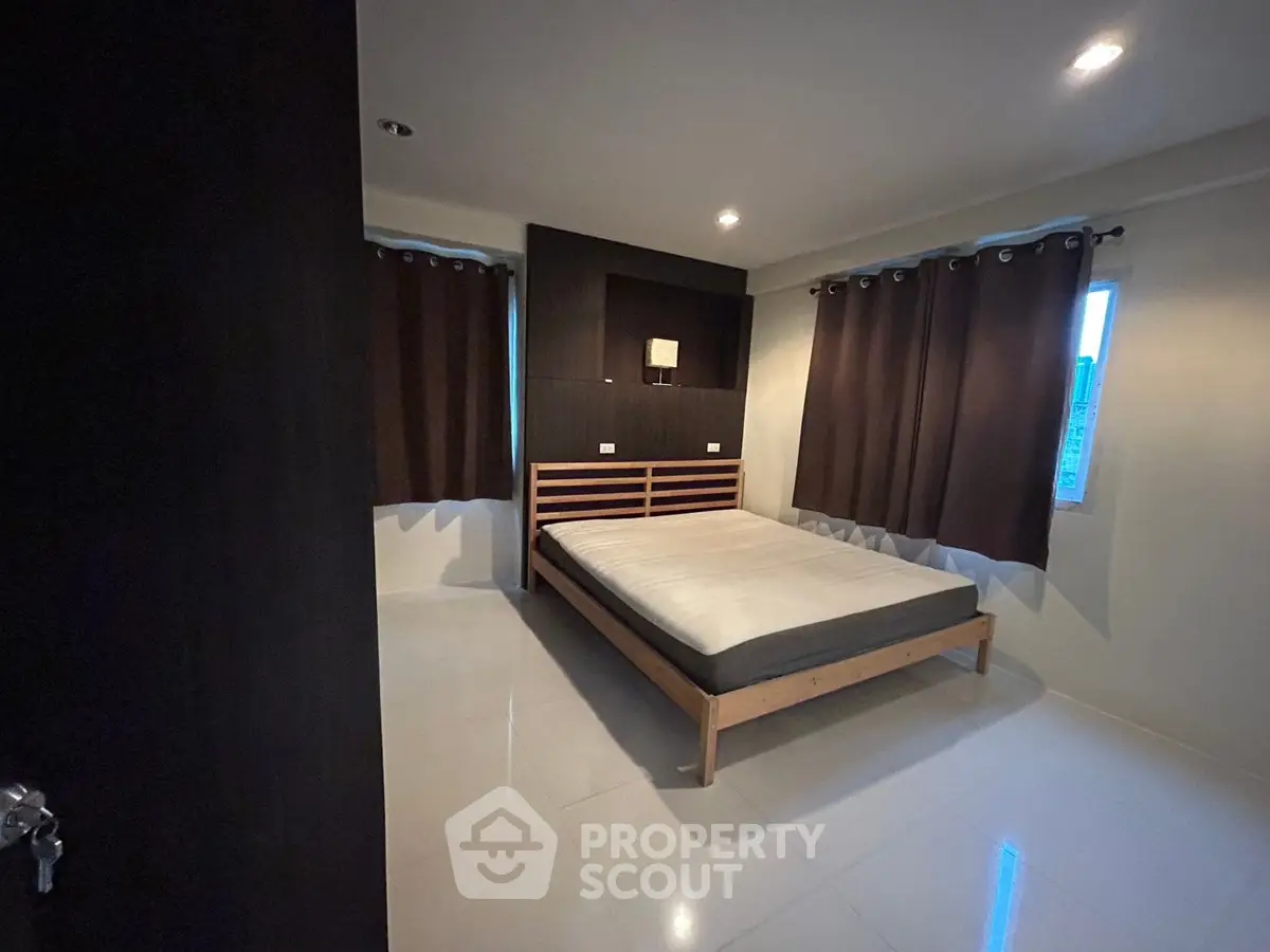 Modern bedroom with sleek design and ample natural light, featuring a comfortable bed and stylish curtains.