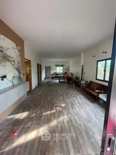 Spacious open-plan living area with modern marble accents and wooden flooring