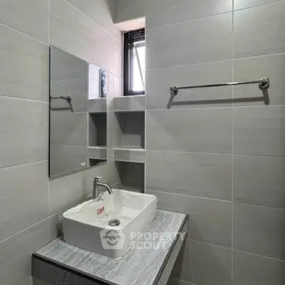 Modern bathroom with sleek sink and mirror, featuring minimalist design and natural light.